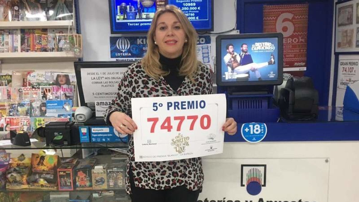 La vendedora de La Bañeza posa orgullosa con una copia del décimo premiado.