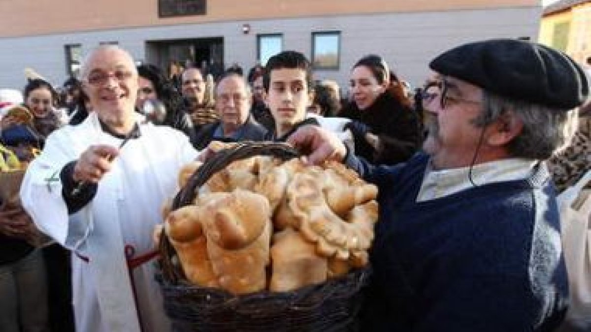 El párroco y los fieles, durante la bendición de los panes ayer en la parroquia cacabelense.