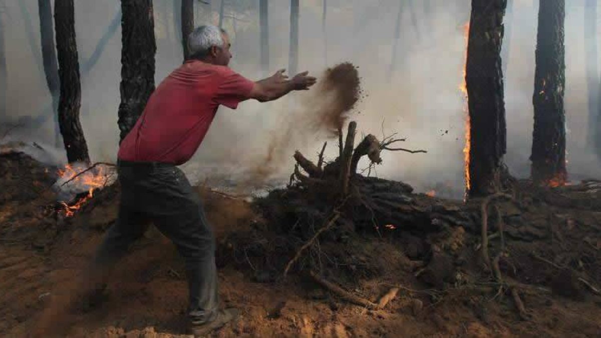Uno de los vecinos de Tabuyo suelta tierra con rabia contra las llamas para tratar de apagarlas.