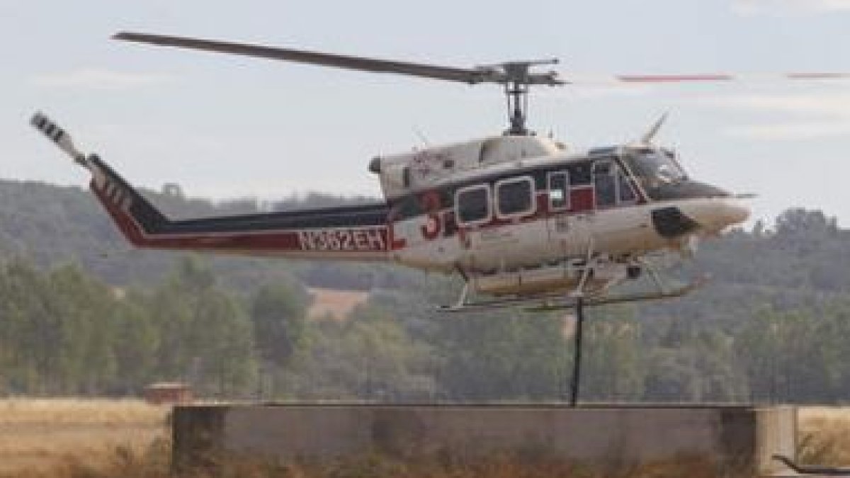 Un helicóptero carga agua en un pozo de uso agrícola.