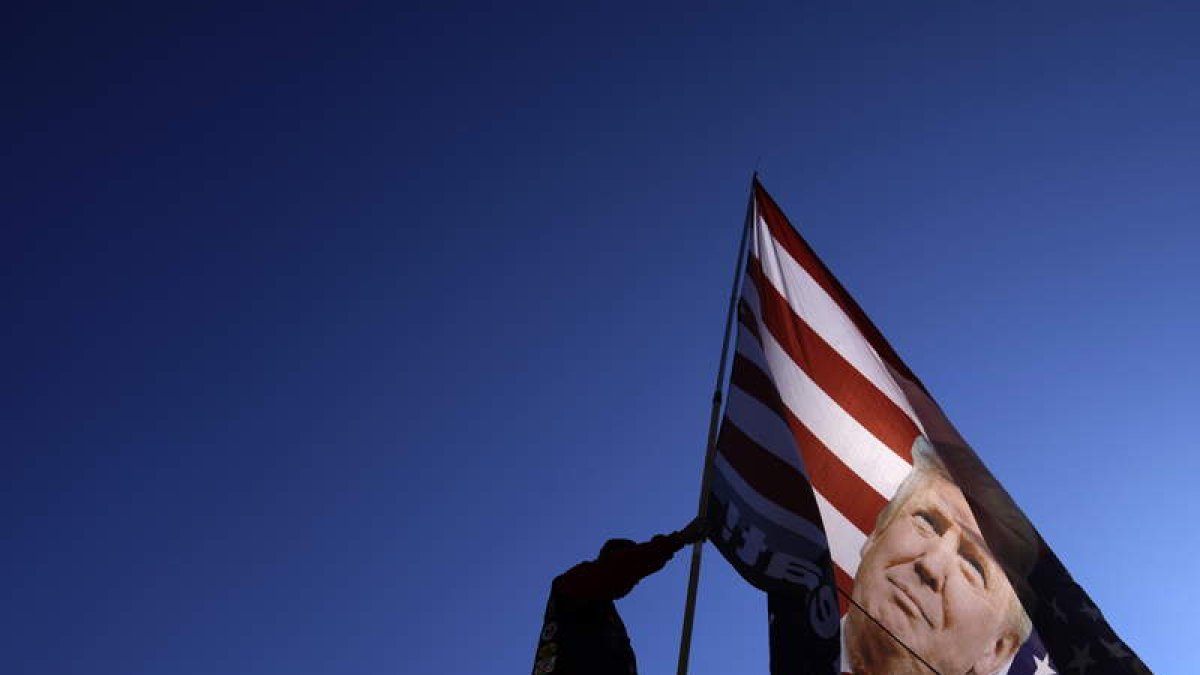Un americano arría una bandera con la efigie de Donald Trump. WILL OLIVER
