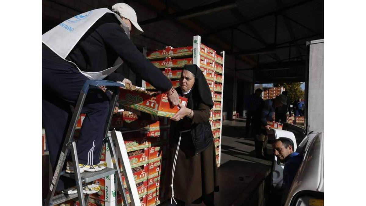 Juani Pérez, la directora, reparte los lotes a los voluntarios para que los entreguen a las personas que llegan pidiendo alimentos.