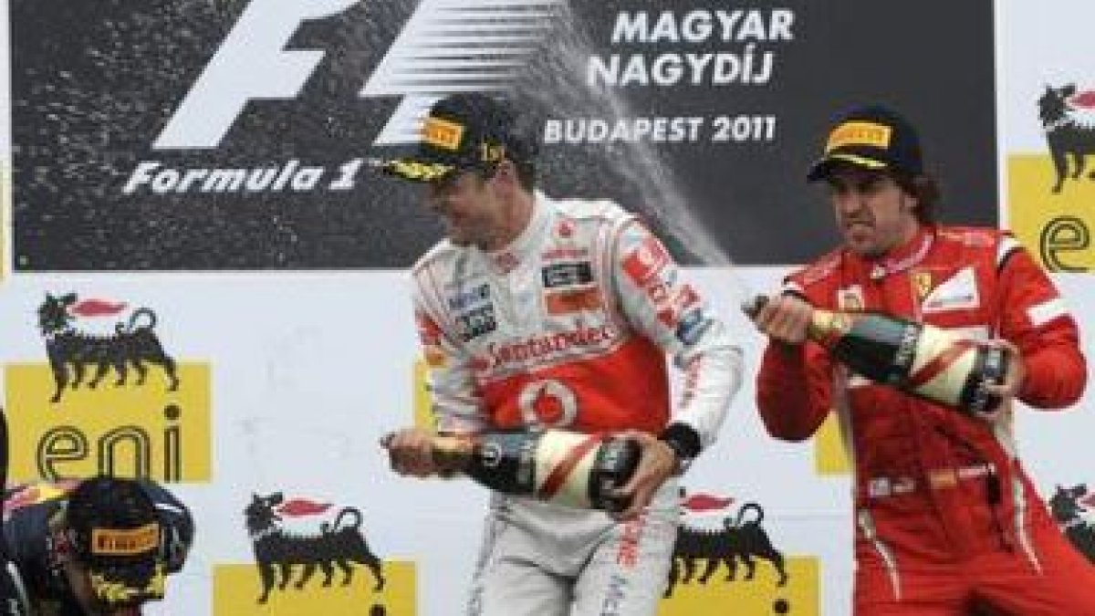 Jenson Button, regado con cava por Fernando Alonso, celebra su segundo triunfo en el Mundial de 2011