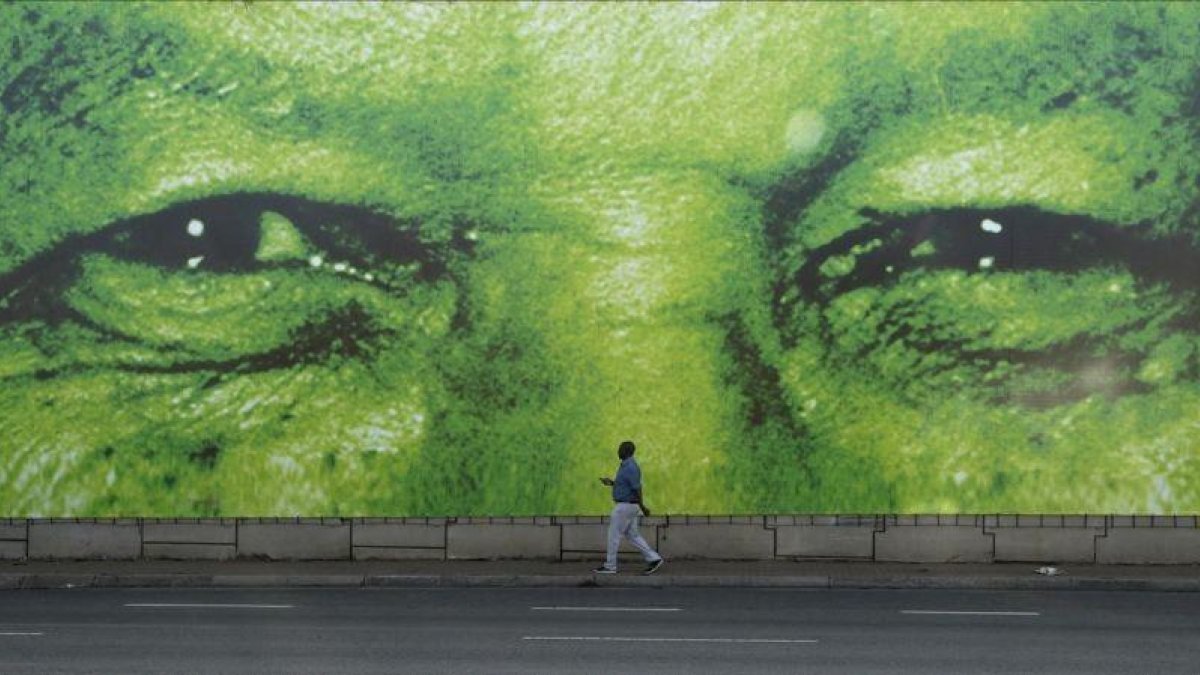 Un hombre pasa en frente de un gigante mural del histórico presidente sudafricano, Nelson Mandela.