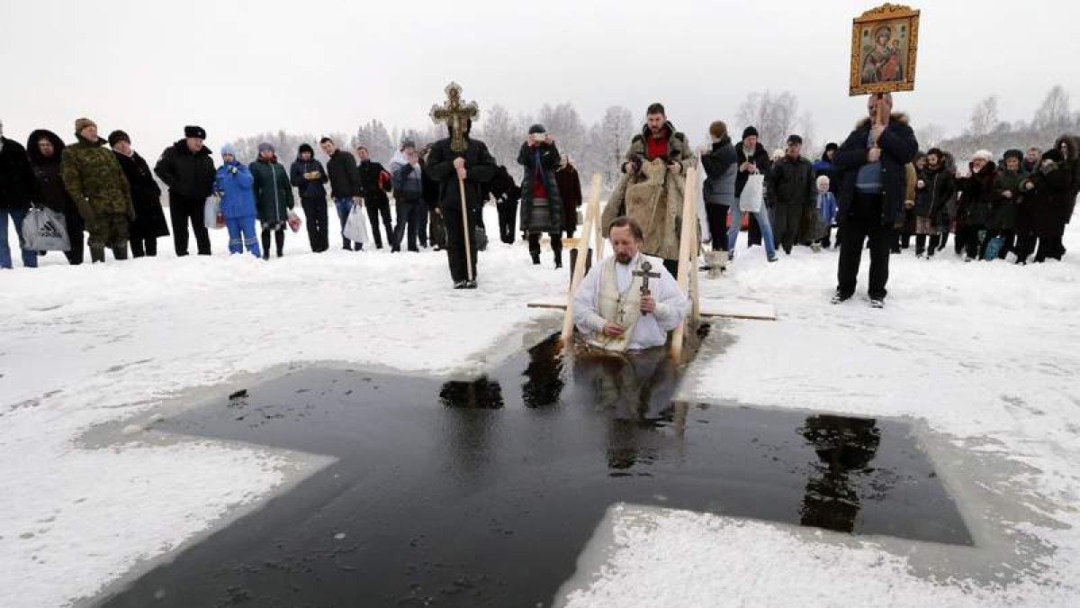 Un sacerdote cristiano ortodoxo se sumerge en agua helada durante la Epifanía en San Petersburgo, Rusia.
