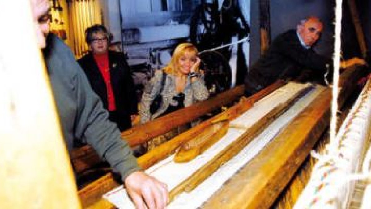La presidenta de la Diputación, Isabel Carrasco, observa el manejo de un antiguo telar el día de la
