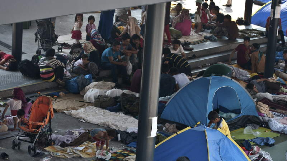 Refugiados intentan conseguir billetes en Budapest para subirse a algún tren a Occidente.