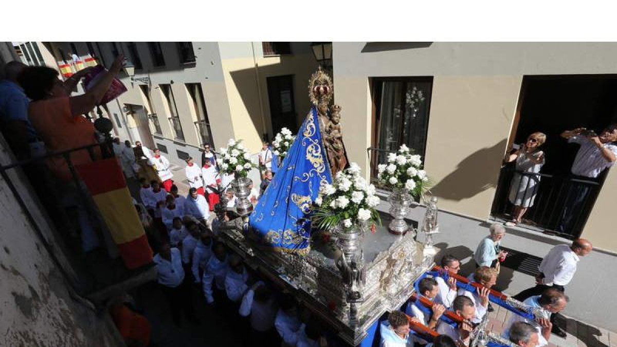 Una mujer arroja unos ramos de hierbabuena desde su balcón al paso de la imagen de la Virgen de la Encina