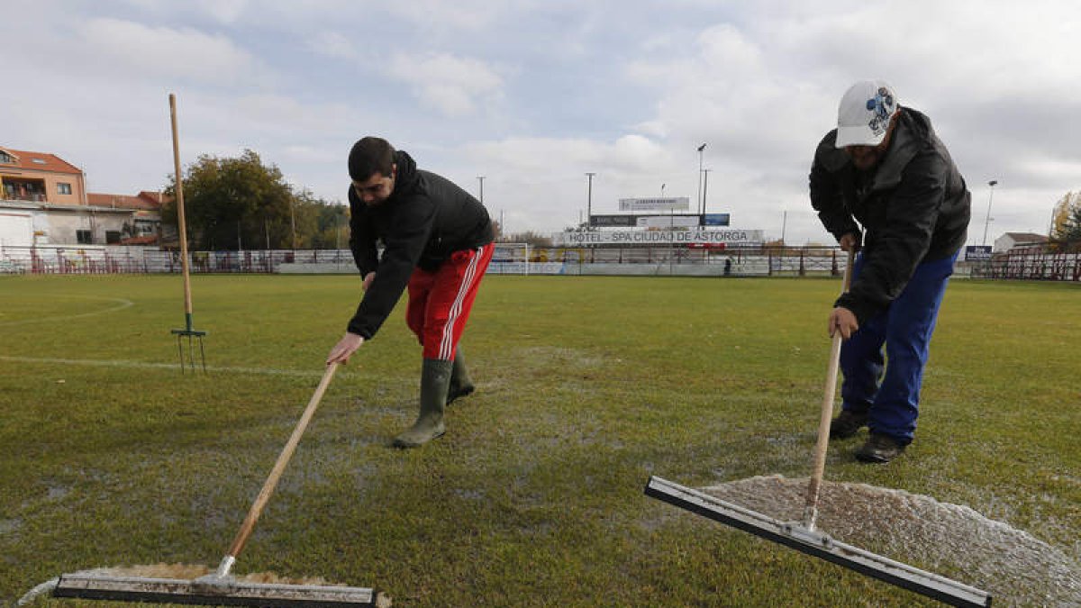 Dos operarios trabajan sobre el césped del estadio maragato.