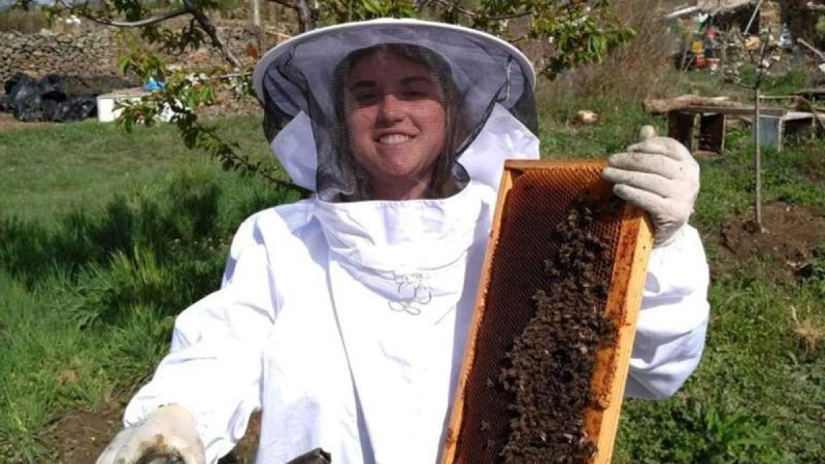 Belén Blanco posando junto a un panel con cientos de abejas. DL