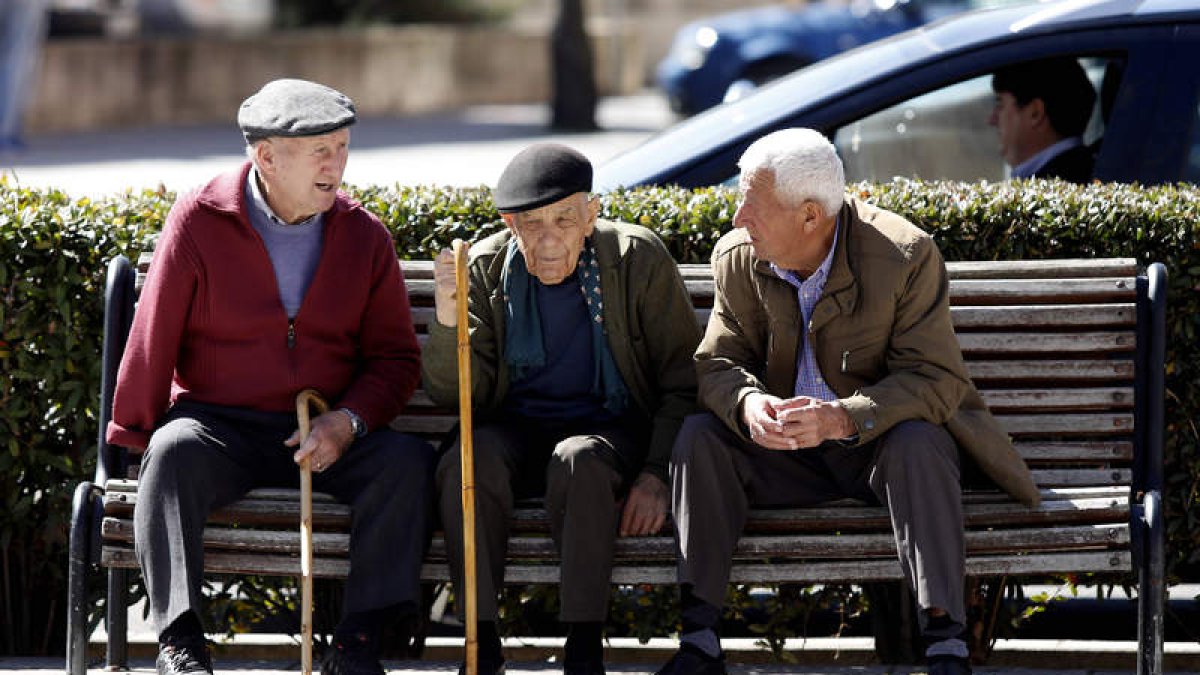 Tres jubilados charlan animadamente en un banco público. M.P.