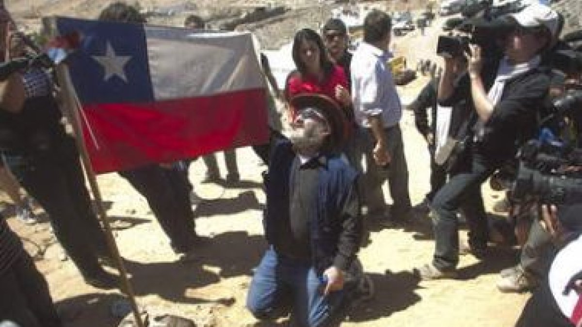El minero Jorge Galleguillos toma una bandera de Chile marcada con su nombre.