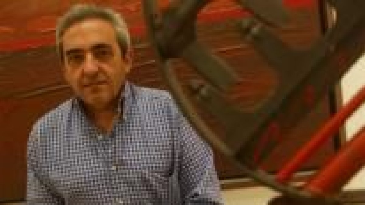 El pintor leonés Ramón Villa posando junto a una de las obras que expone en la Sala Provincia