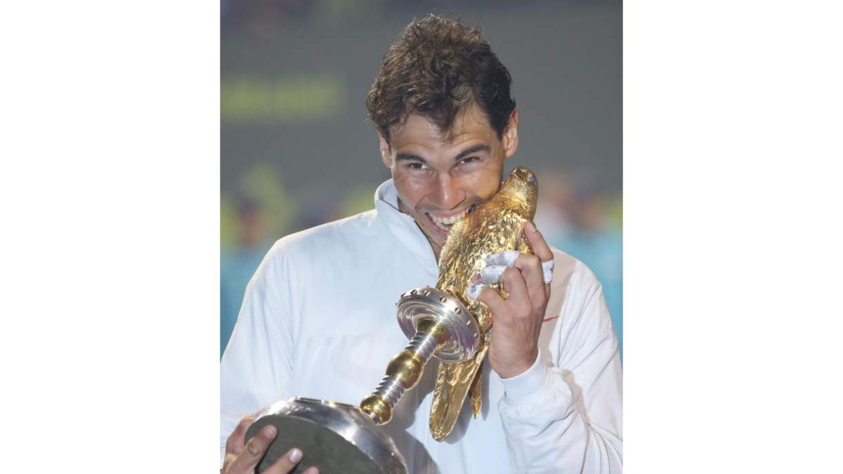 Nadal muerde el trofeo que le acredita como campeón en Doha.