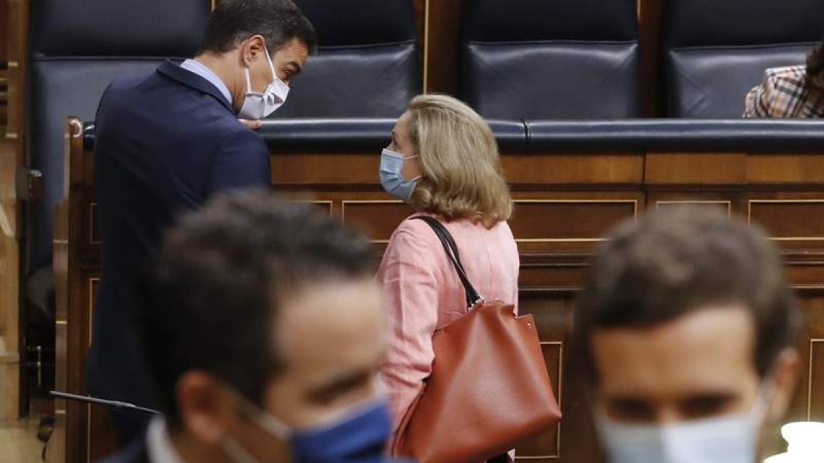 Pedro Sánchez conversa con Nadia Calviño; a su espalda el popular Pablo Casado, en el Congreso de los Diputados. BALLESTERIOS