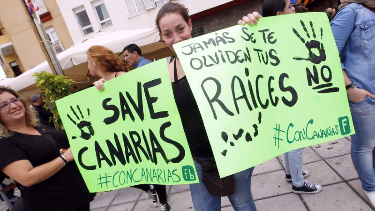 Dos jovenes protestan con pancartas contra las prospecciones petrolíferas en Canarias.