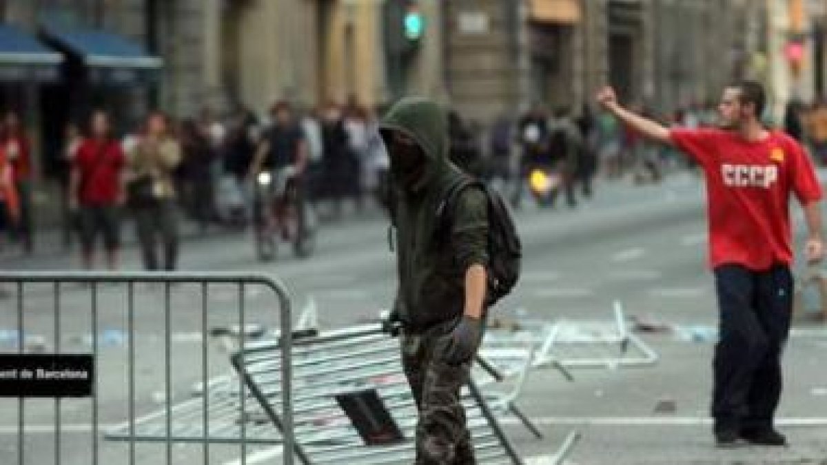 Un joven forma una barricada con vallas durante la manifestación en Barcelona.