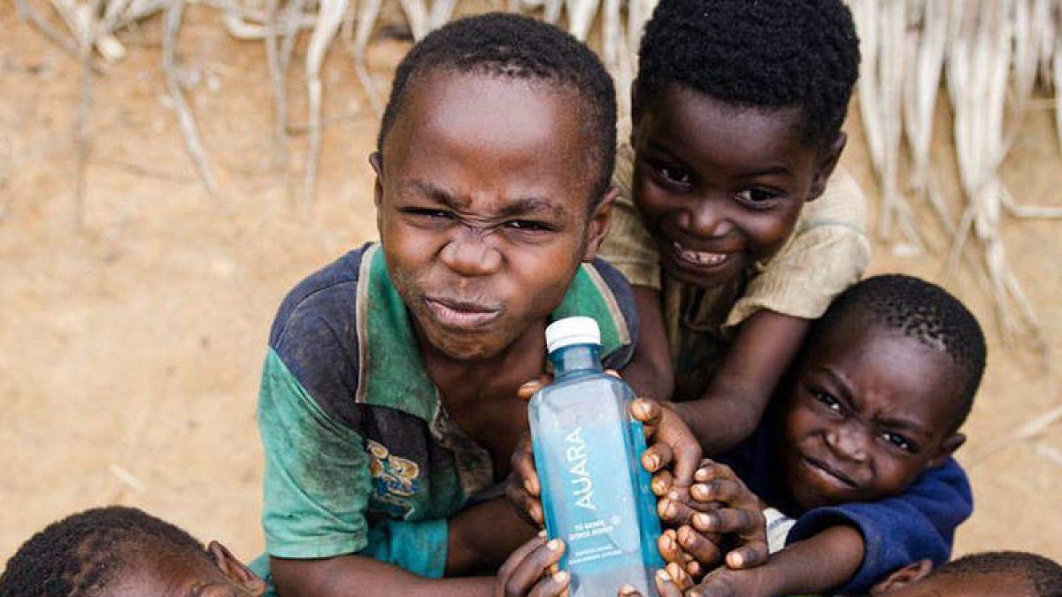 Niños haitianos con el agua embotellada en León. DL