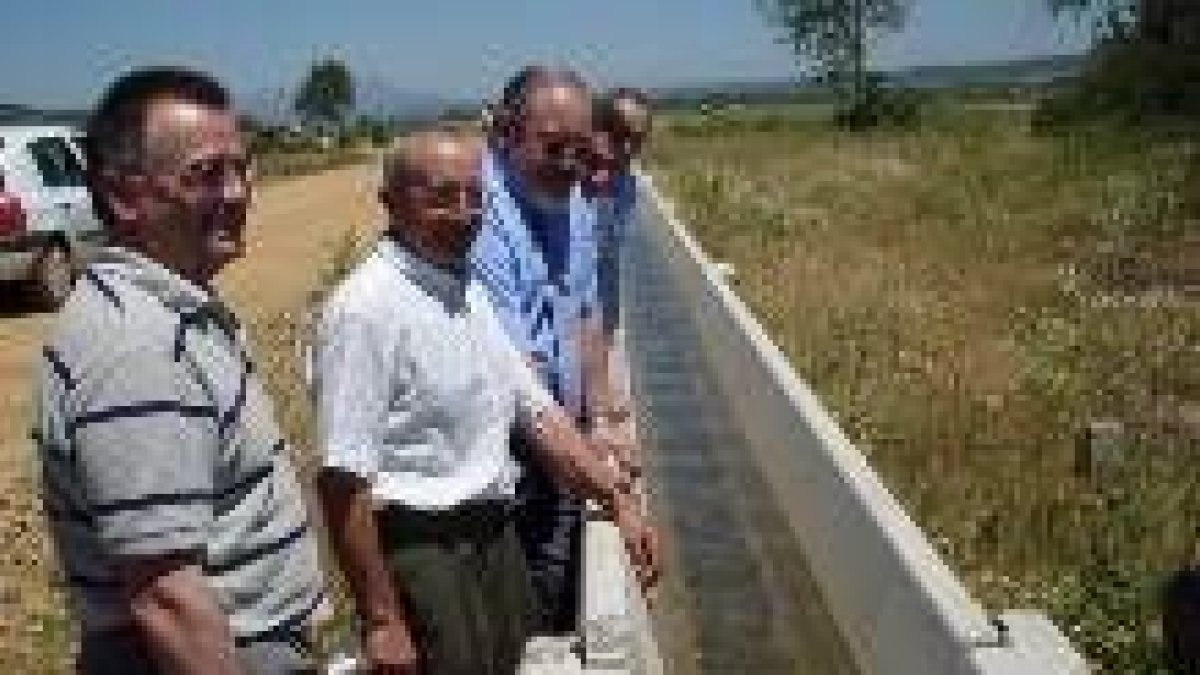 José Valín, tercero por la izquierda, observa una acequia que inauguró en un nuevo regadío de León