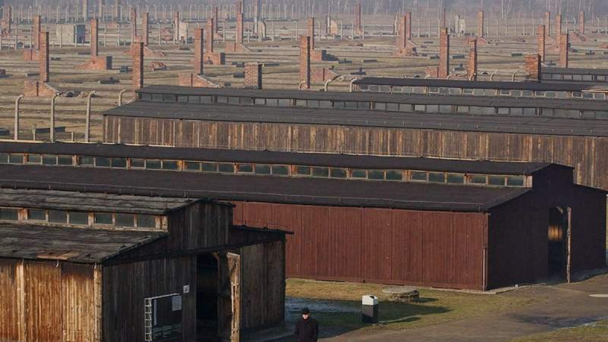 Un hombre camina entre los barracones del campo de concentración de Auschwitz