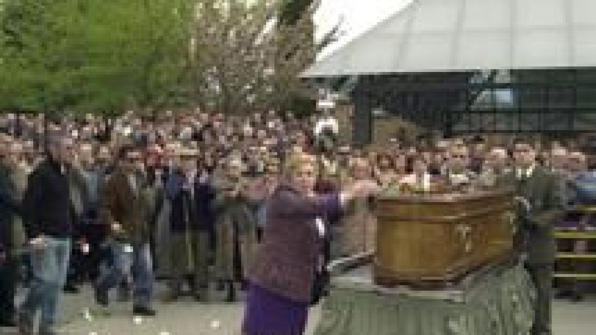 Una mujer deposita flores sobre el féretro de José Couso. A la izquierda, su compañero Jon Sistiaga