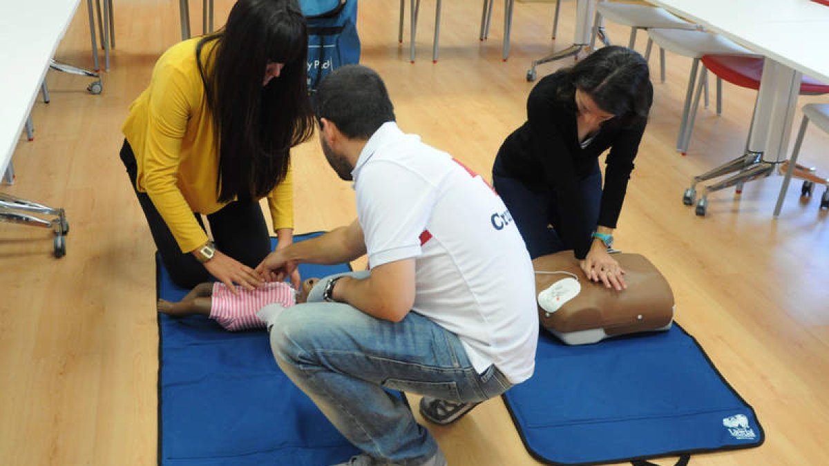 Dos alumnas aprenden a dar masajes cardiacos con dos maniquíes de Cruz Roja. JAVIER SUÁREZ-QUIÑONES