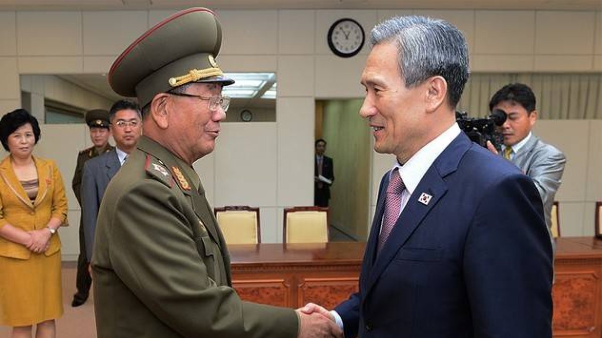 El ministro surcoreano de Unificación, Kim Kwan-jin, a la derecha, da la mano a Hwang Pyong So, responsable norcoreano, tras alcanzar el acuerdo para rebajar la tensión.