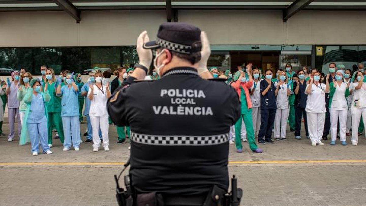 Un policía local y sanitarios del Hospital La Fe de Valencia, durante el aplauso diario. BIEL ALIÑO