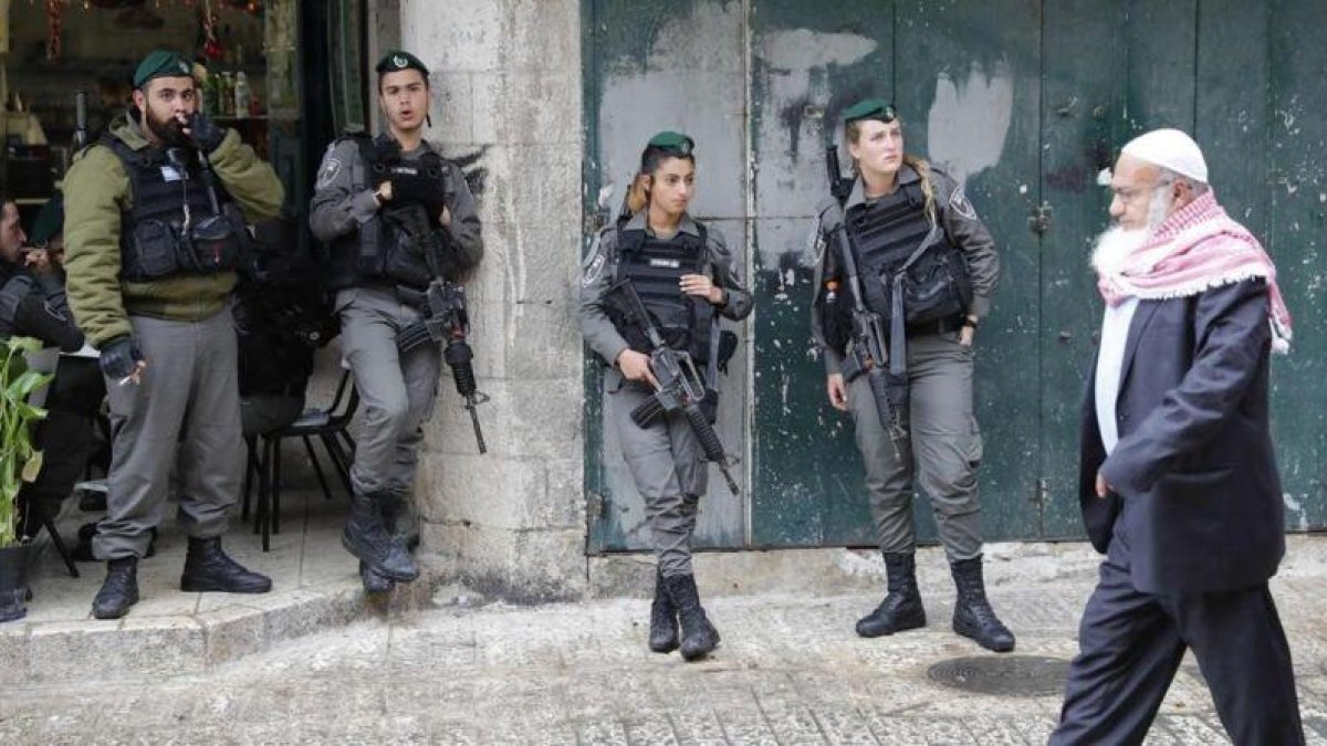 Un palestino camina ante un grupo de soldados israelís en la ciudad antigua de Jerusalén.