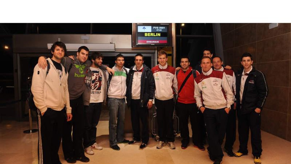 La plantilla leonesa a su llegada a Alemania se coloca debajo del cartel de vuelo con el nombre de la capital germana y su último escollo antes de alcanzar por primera vez en su historia la Final Four.