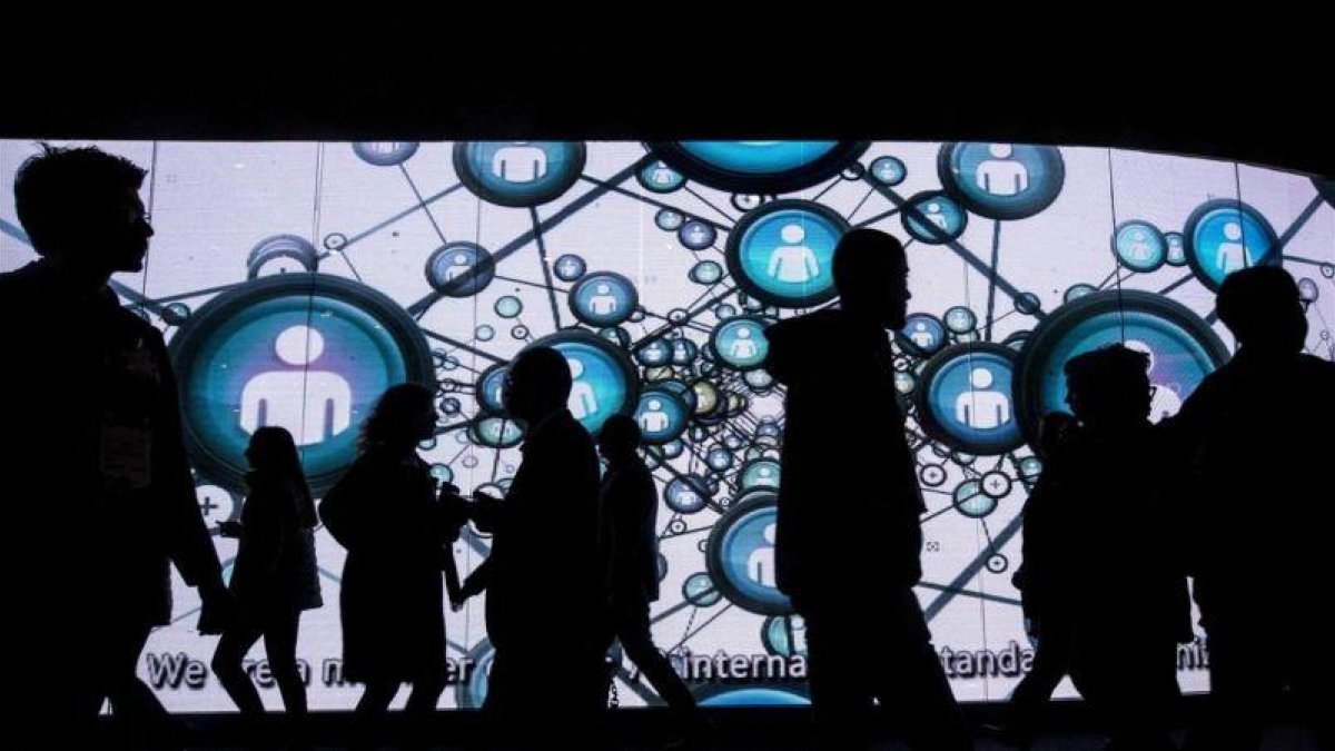 Visitantes del Mobile World Congress ante una enorme pantalla.