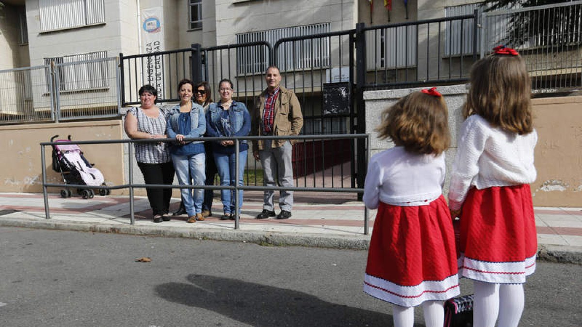 Dos pequeñas que acuden al comedor del Antonio Valbuena posan en el colegio con un grupo de madres y padres