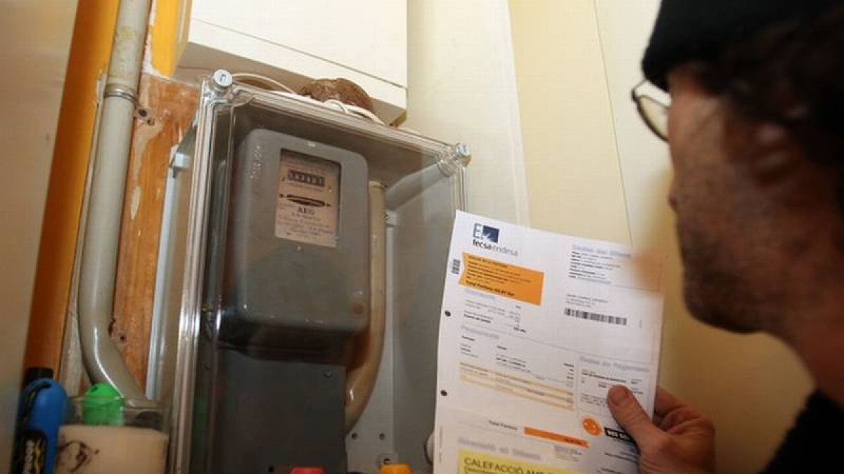 Un joven repasa la factura de la luz junto al contador.