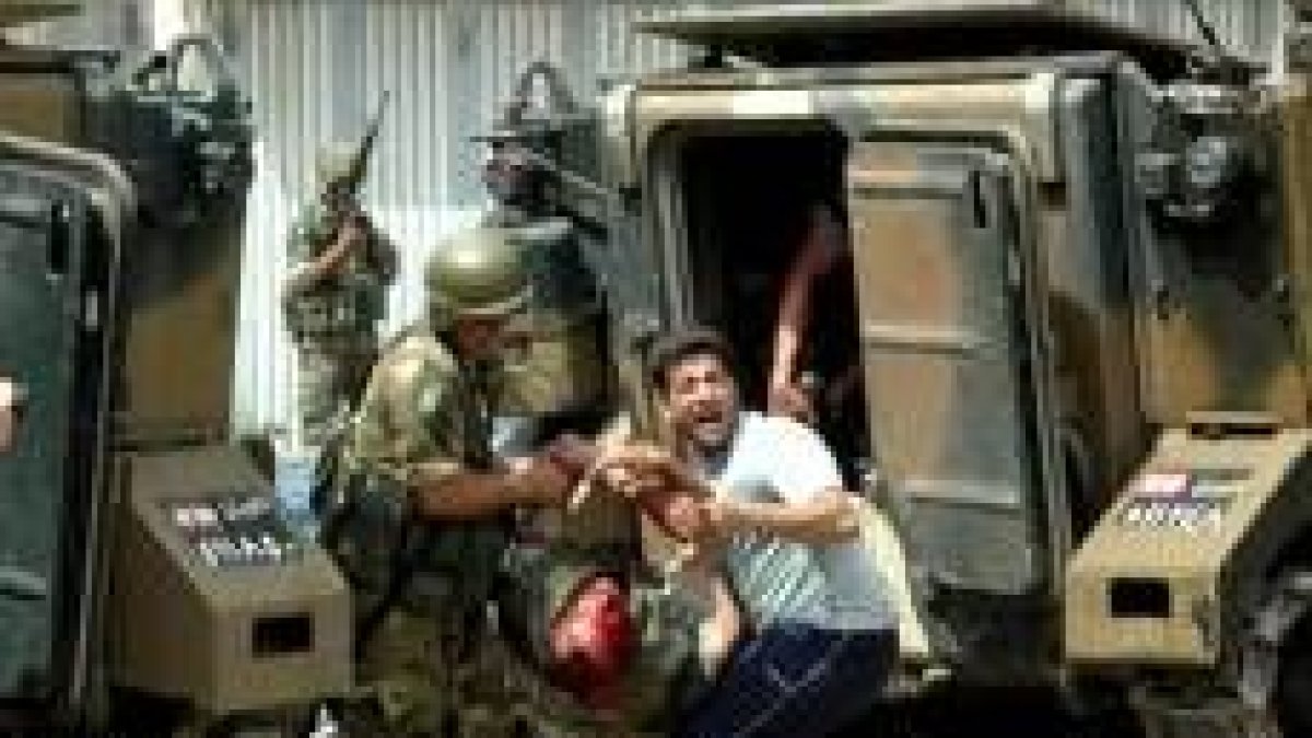 Un soldado y un miembro de seguridad intentan trasladar a un militar herido en los enfrentamientos
