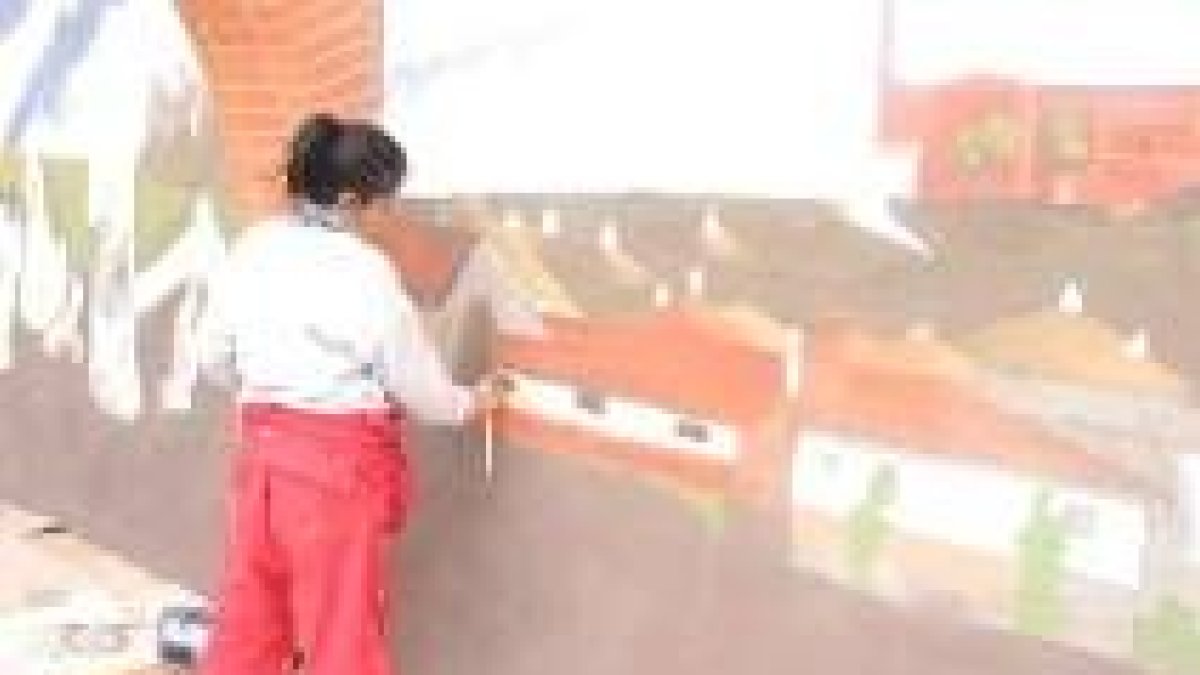 La joven artista Nonia Villa trabajando en el mural de la iglesia