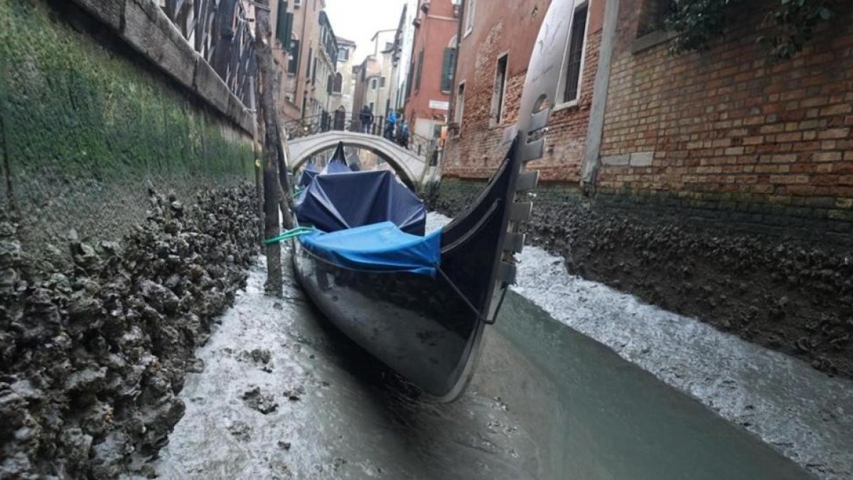 Una gondola permanece amarrada en un canal practicamente sin agua en Venecia.