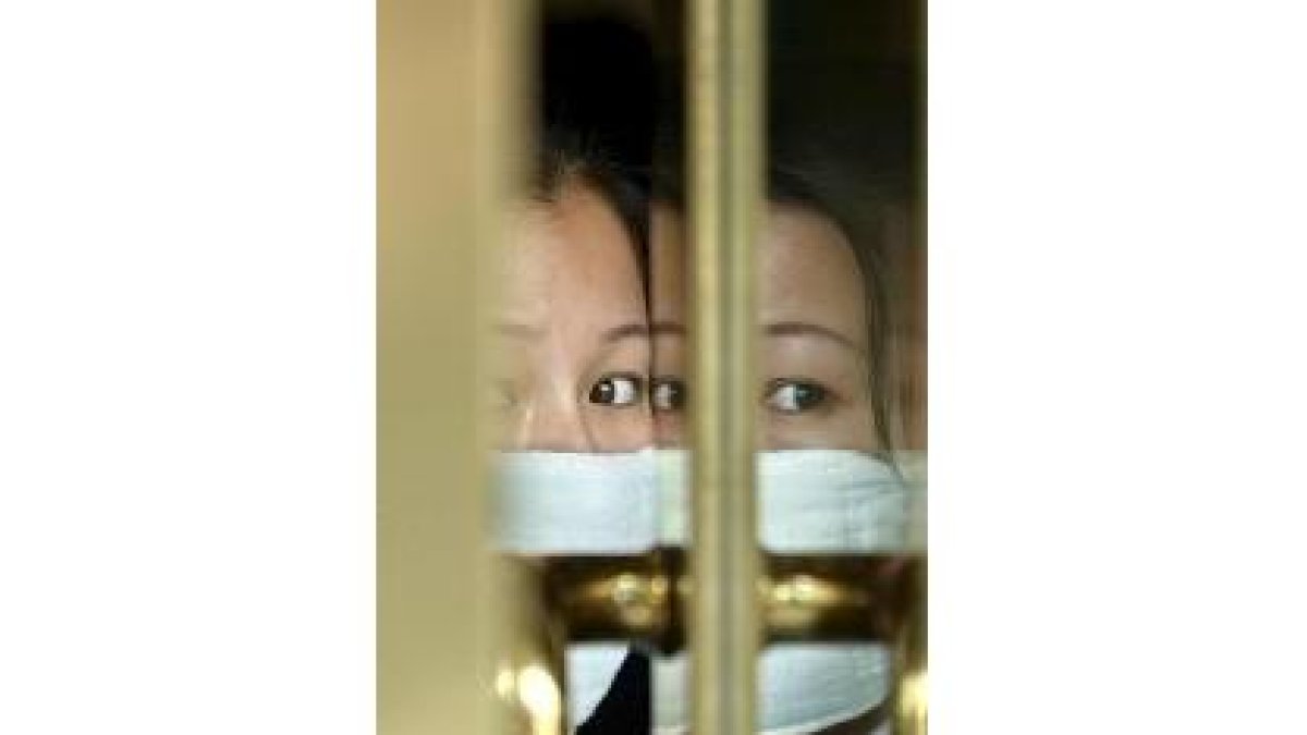 El rostro de una mujer se refleja en el cristal de un restaurante en Pekín