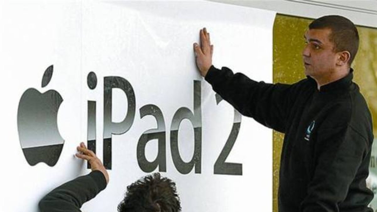 Renovación 8 Dos trabajadores cuelgan carteles del iPad 2 en Berlín.