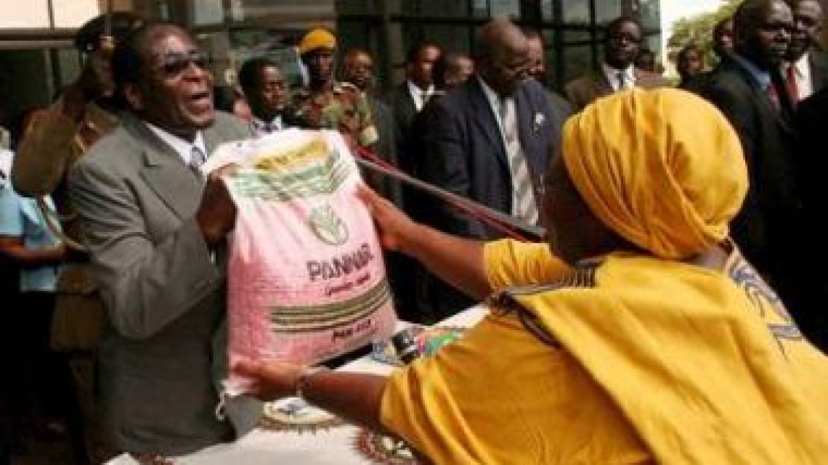 Mugabe entrega un saco de maíz a una simpatizante del partido Zanu