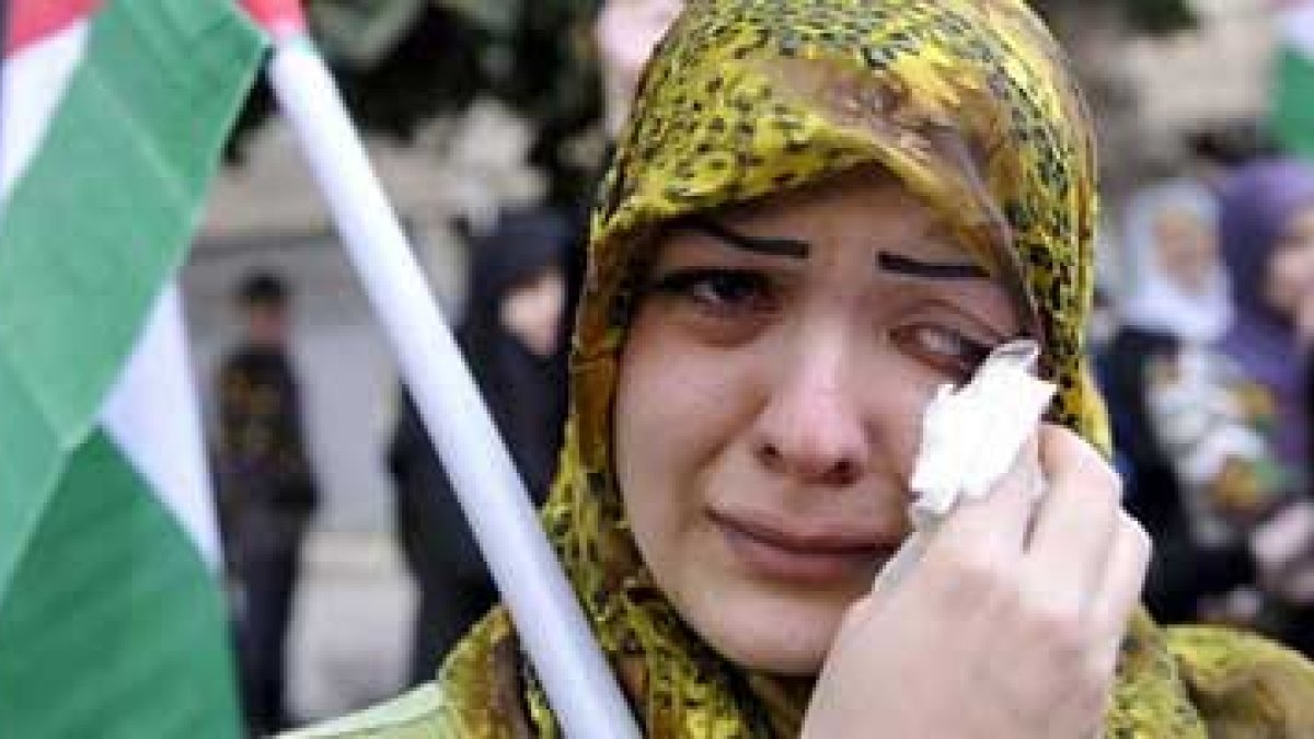 Una mujer libanesa llora mientras sostiene una bandera palestina.