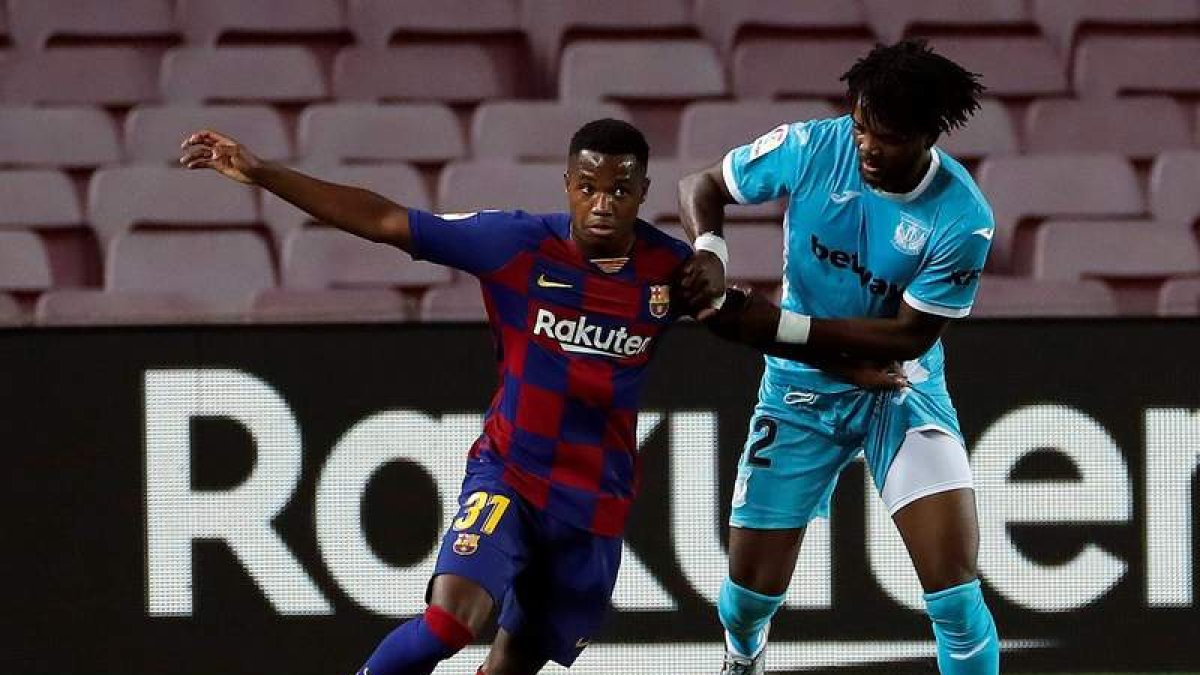 El delantero del Barcelona Ansu Fati juega un balón ante Chidozie Awaziem, del Leganés. A. ESTÉVEZ