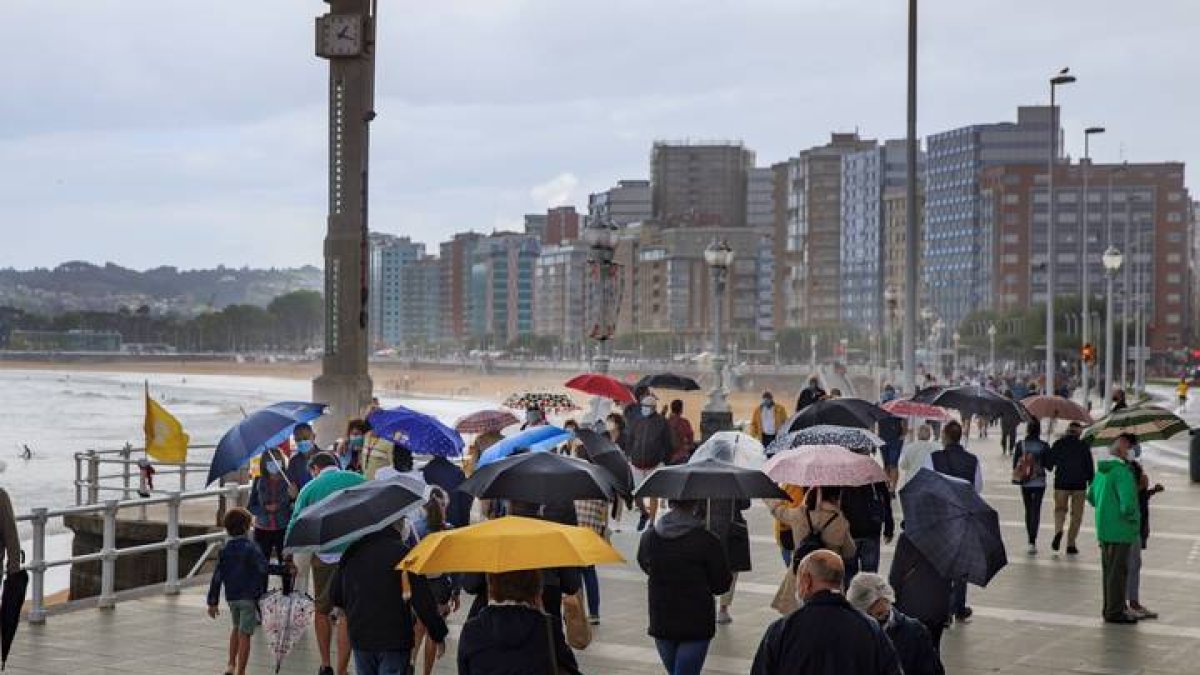 Decenas de personas pasean este domingo por la playa de San Lorenzo. ALBERTO MORANTE