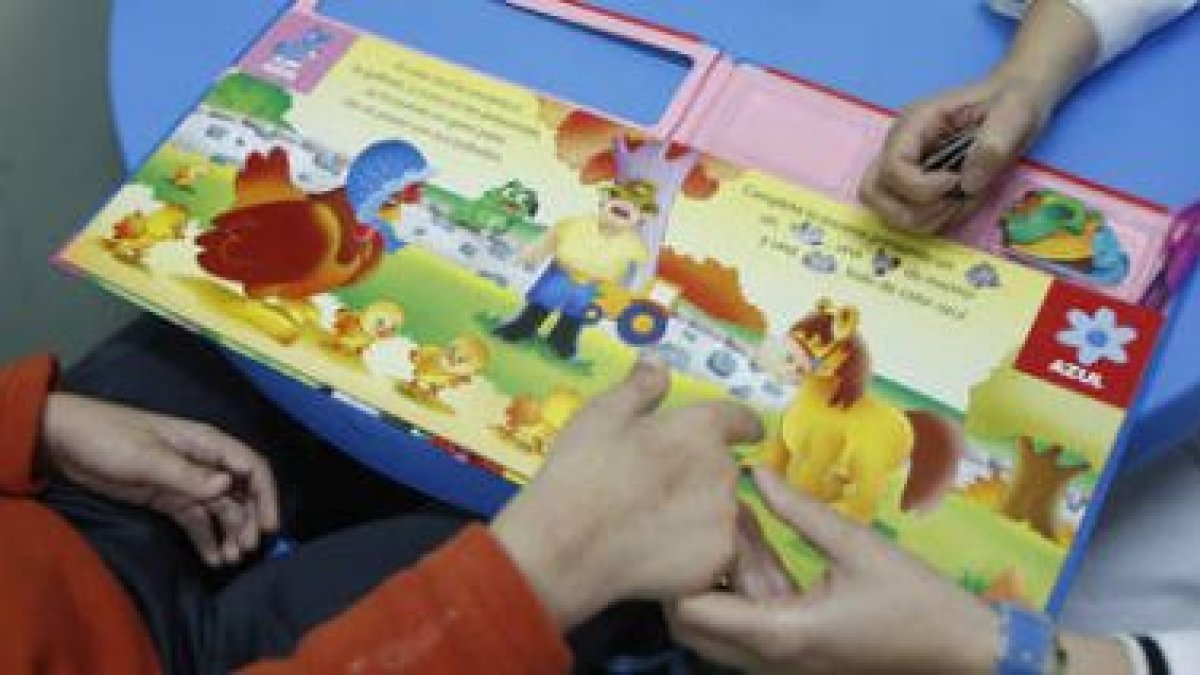 Un educador atiende mediante un juego a un niño con problemas de comunicación.