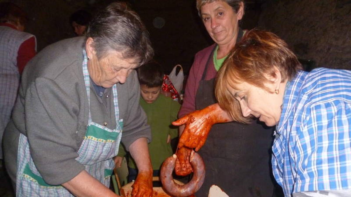 Unas mujeres preparan los chorizos que más tarde iban a ser degustados.