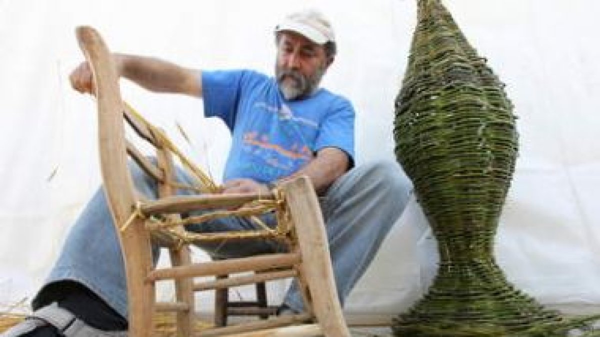 Un artesano hace una demotración de la elaboración de una silla de paja.