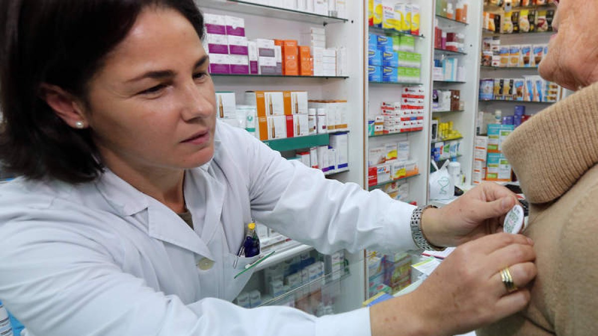 Una farmacéutica de León coloca una de las chapas