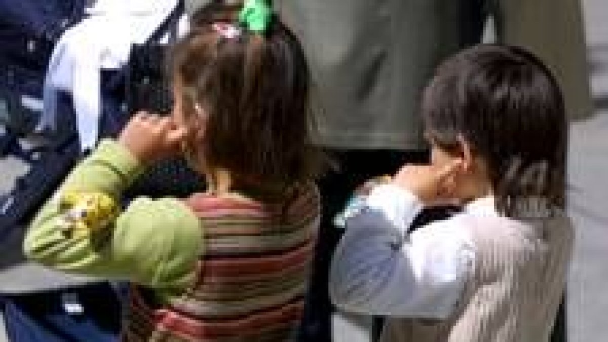Dos niños se tapan los oídos para protegerse del ruido de unos petardos en unas protestas