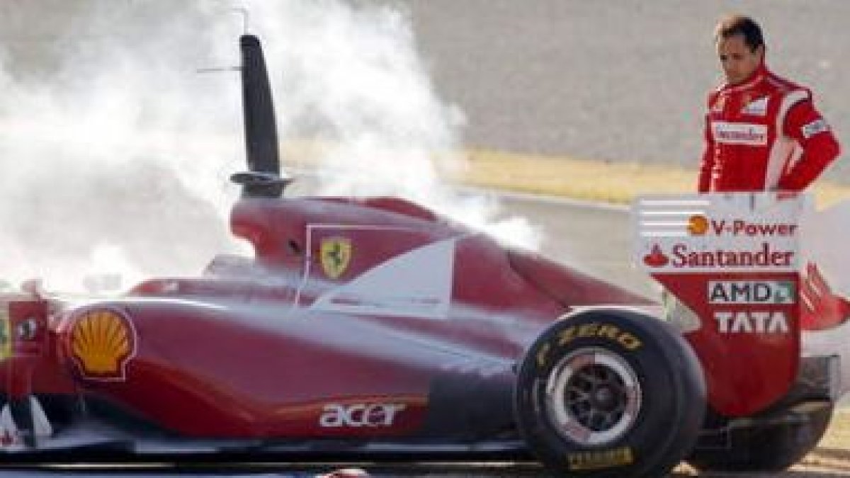 El brasileño de Ferrari, Felipe Massa, contempla su coche tras incendiarse el motor.