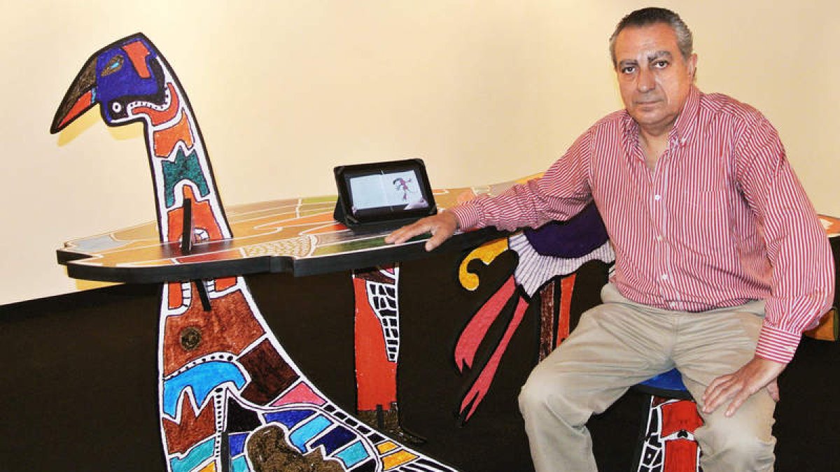 Adolfo Alonso Ares, con una de sus esculturas y una pantalla con versos e ilustraciones.