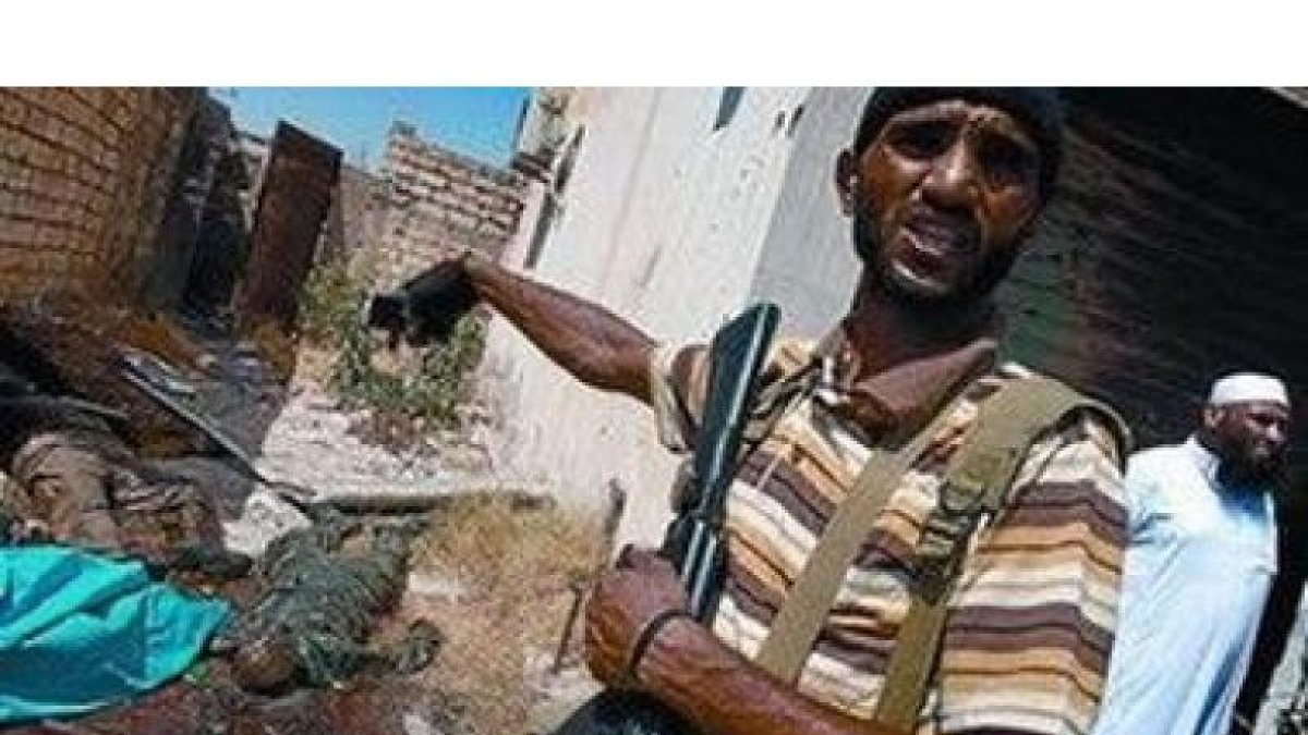 Un combatiente rebelde muestra los cuerpos de dos soldados gadafistas muertos en Zawiya.